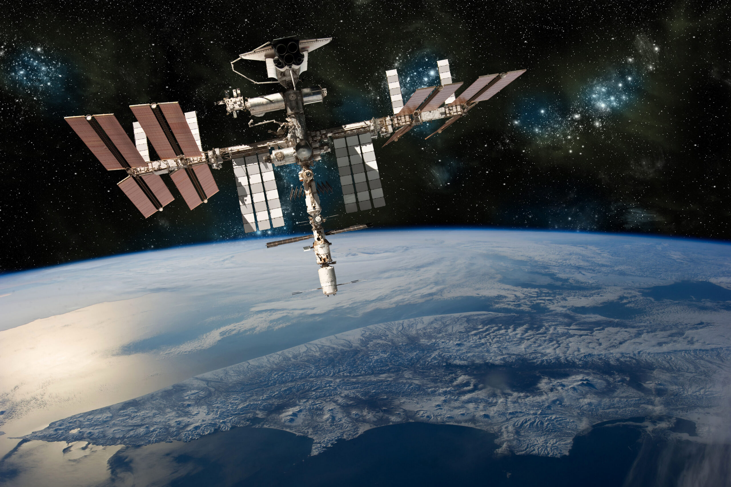 A depiction of the space shuttle docked at the international space station orbiting Earth. – Elements of this image furnished by NASA